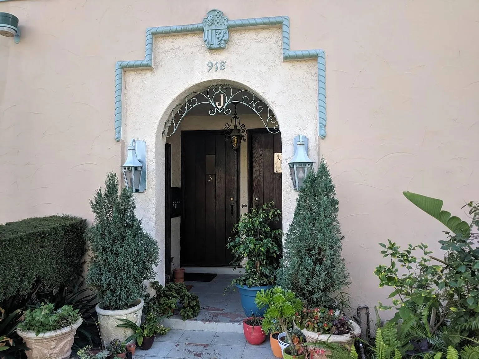 The arched entry with the plaster crest and the numerals 918 above a dark wood door.