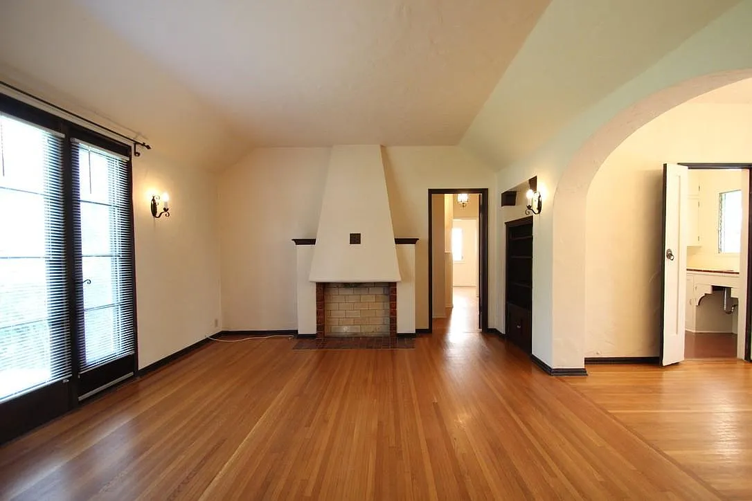Living room with a tiled fireplace, vaulted ceiling and refinished hardwood floors.
